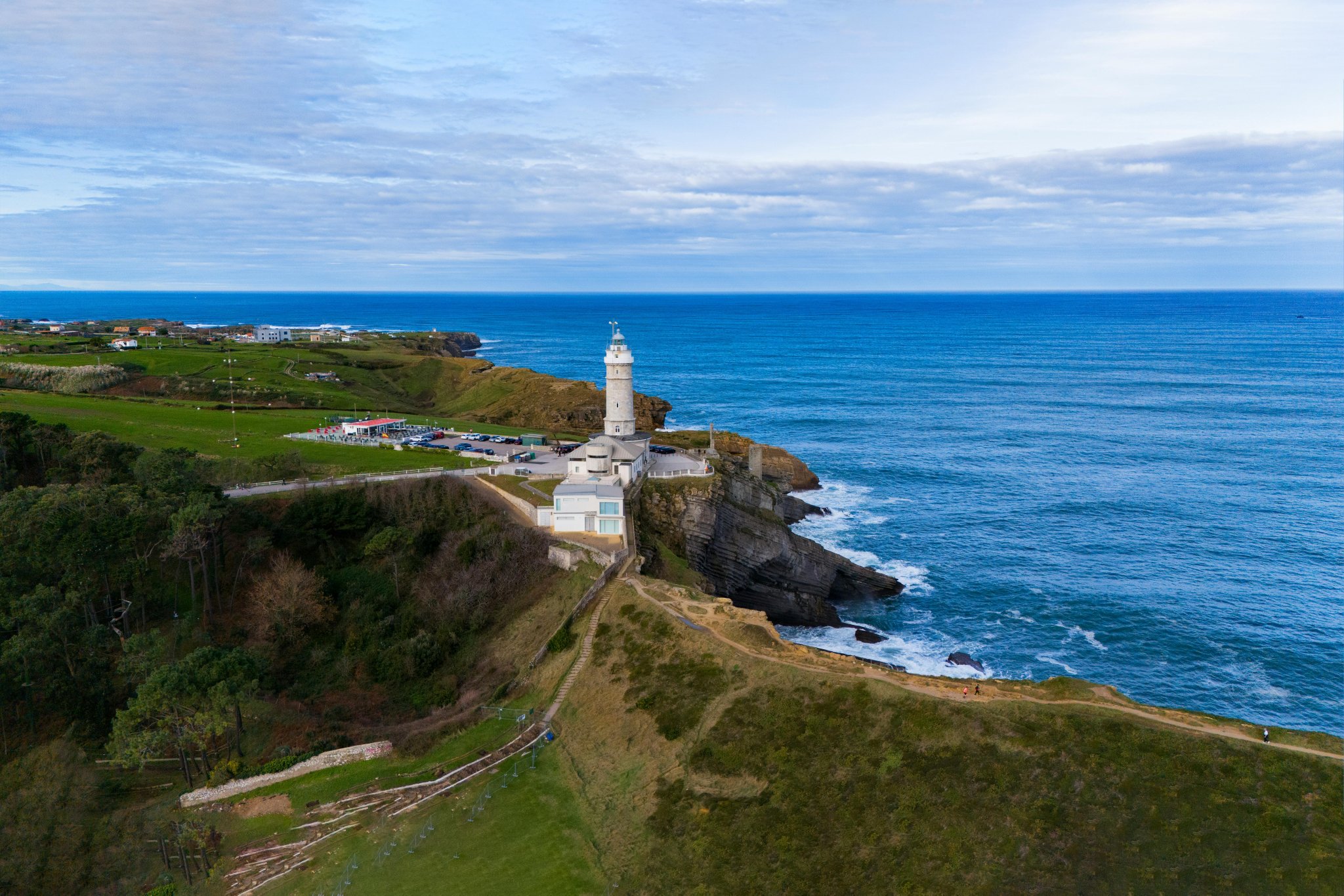 A lighthouse overlooks the ocean from a rugged coastline, symbolizing guidance, resilience, and steadfast leadership for blue-collar workplace wellness programs that help employees navigate everyday challenges.