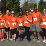 Group of individuals preparing for a group race. All wearing running bibs and orange shirts.