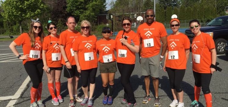 Group of individuals preparing for a group race. All wearing running bibs and orange shirts.