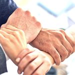 Group of four people holding another's wrist to make a square. 13 Fun Workplace Wellness Challenge Ideas Your Employees Will Enjoy