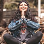 Young woman sitting on the ground outside meditating and smiling. benefits of meditation and mindfulness