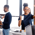 Group of people celebrating in an office with high fives and hugs.