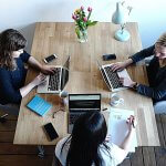 Overhead view of three professionals working at a large table.