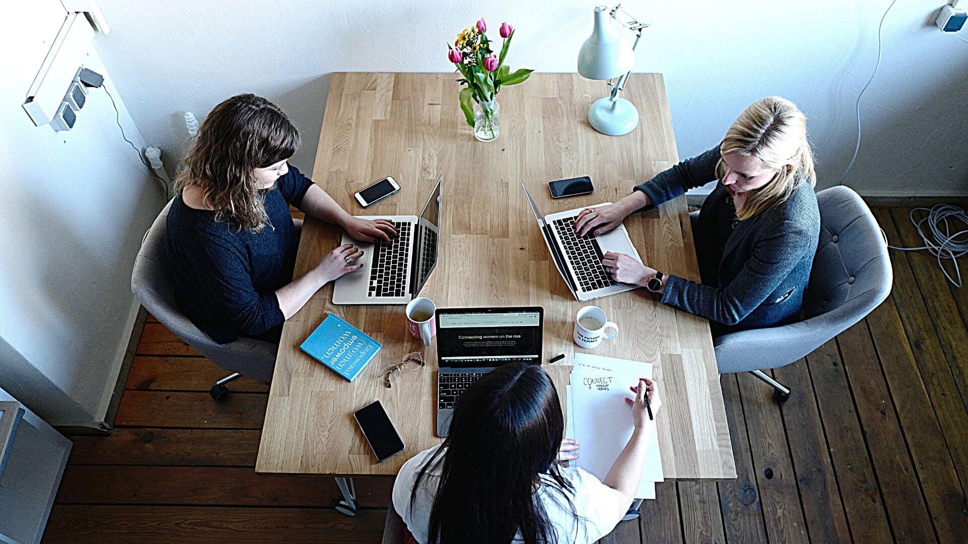 Overhead view of three professionals working at a large table.
