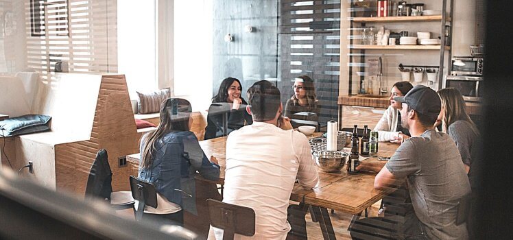 Group of coworkers sitting and laughing at a large table.