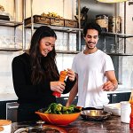 Two people preparing a salad in a large bright kitchen.