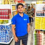 Man in blue shirt standing in a grocery store aisle.