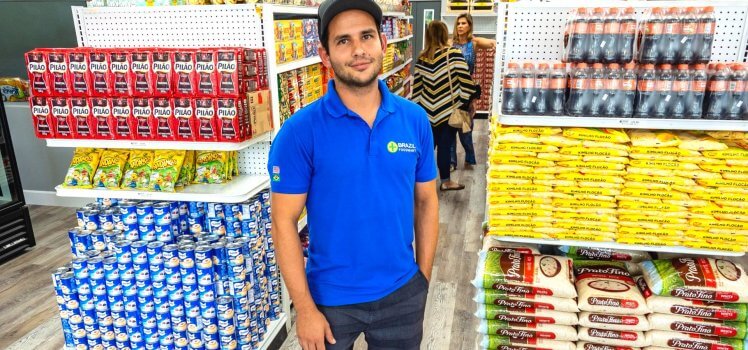 Man in blue shirt standing in a grocery store aisle.