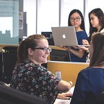 Two sets of two women in an office setting working.