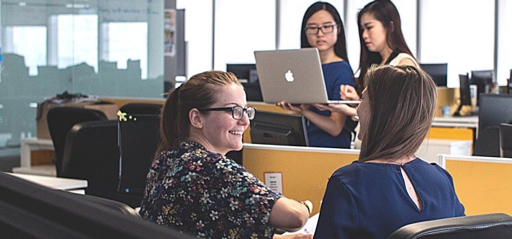 Two sets of two women in an office setting working.