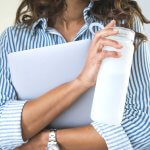 Close up of woman holding white water bottle and tablet.