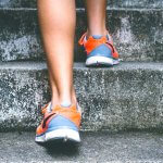 Closeup of person in blue and orange shoes climbiing up stairs. Easy ideas for increased fitness in the workplace