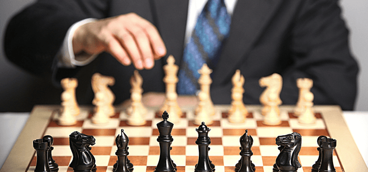 Man in black with a blue tie playing chess, from the opponents viewpoint.