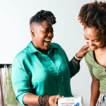 Two women laughing together and standing close.