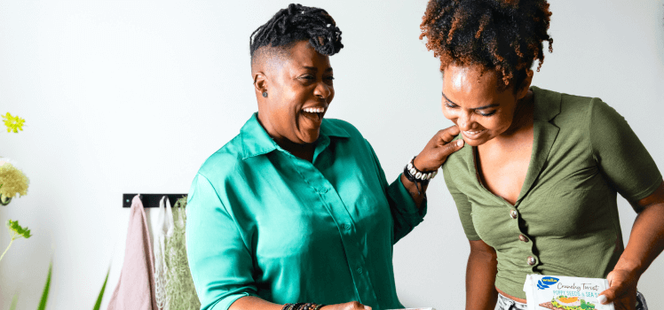 Two women laughing together and standing close.