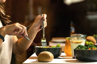 Closeup profile view of a person eating a salad on a table.