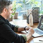 Man sitting at a desk on a video conference call with another woman.