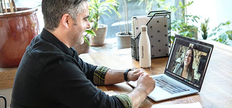 Man sitting at a desk on a video conference call with another woman.