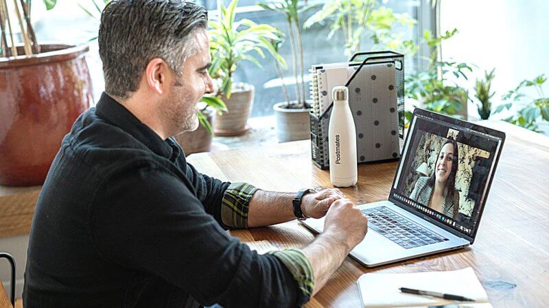 Man sitting at a desk on a video conference call with another woman.