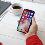 Closeup of a man in a red shirt looking at a phone.