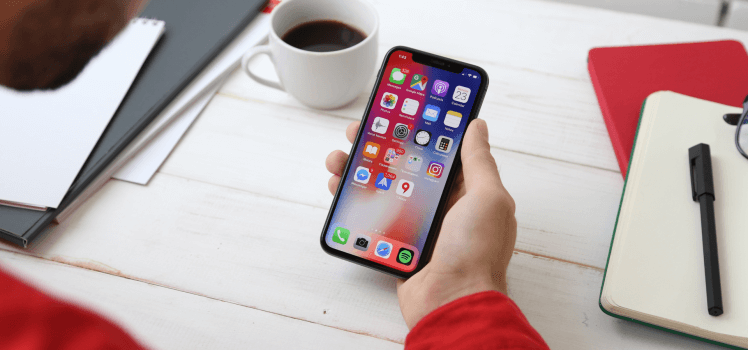 Closeup of a man in a red shirt looking at a phone.