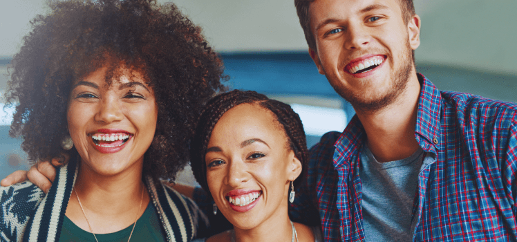 Three young people shoulder to shoulder smiling.