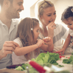 family preparing a salad together and laughing.