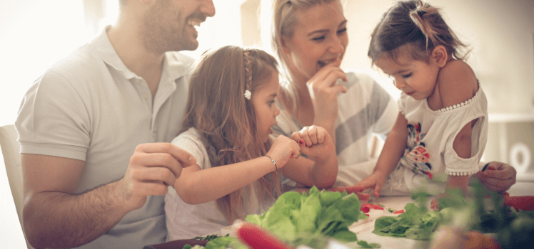 family preparing a salad together and laughing.