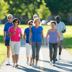 Group of older individuals walking in the park on a sunny day.