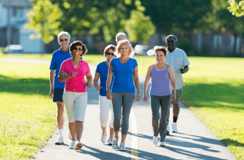 Group of older individuals walking in the park on a sunny day.