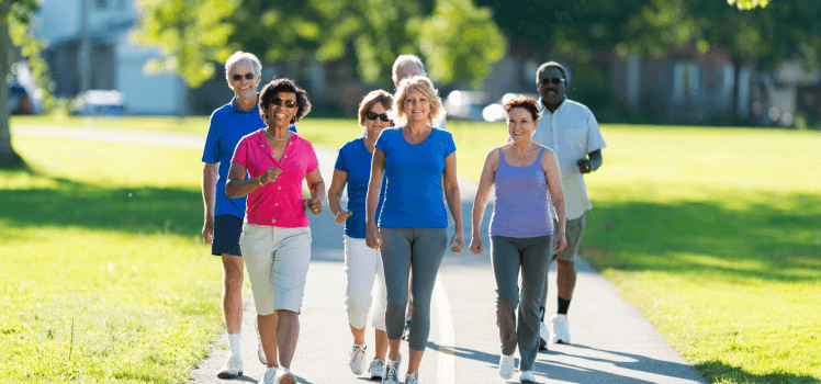 Group of older individuals walking in the park on a sunny day.