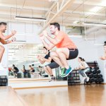 Group exercise class with multiple people almost floating in air as they are mid jump.