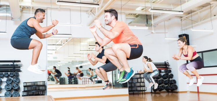 Group exercise class with multiple people almost floating in air as they are mid jump.