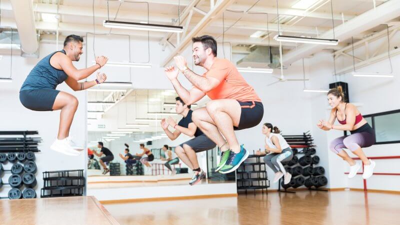 Group exercise class with multiple people almost floating in air as they are mid jump.