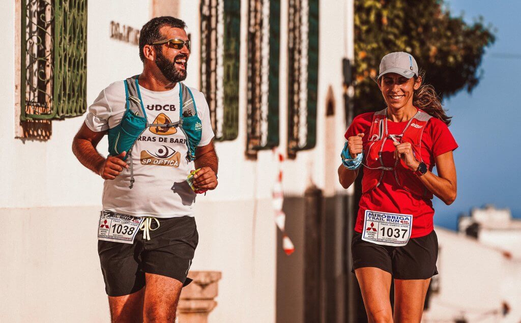 Man and woman laughing and talking while running in a 5k race. 