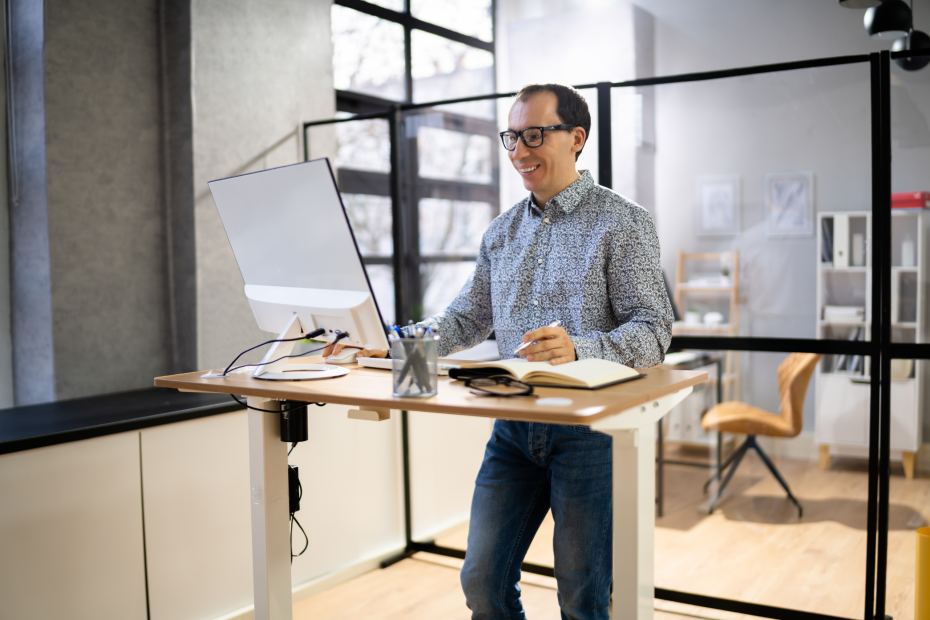 man standing at an adjustable standing desk while at work