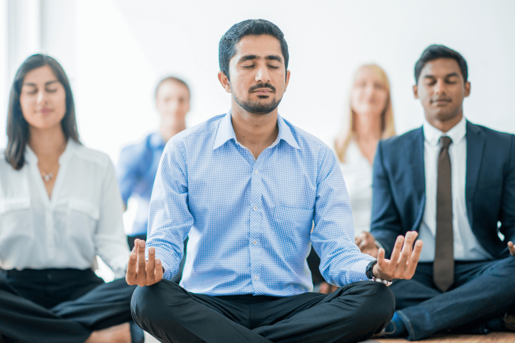 A Group of Professionally Débrés Employees Meditating at Work