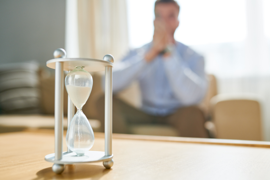 a man looking at an hourglass in his office