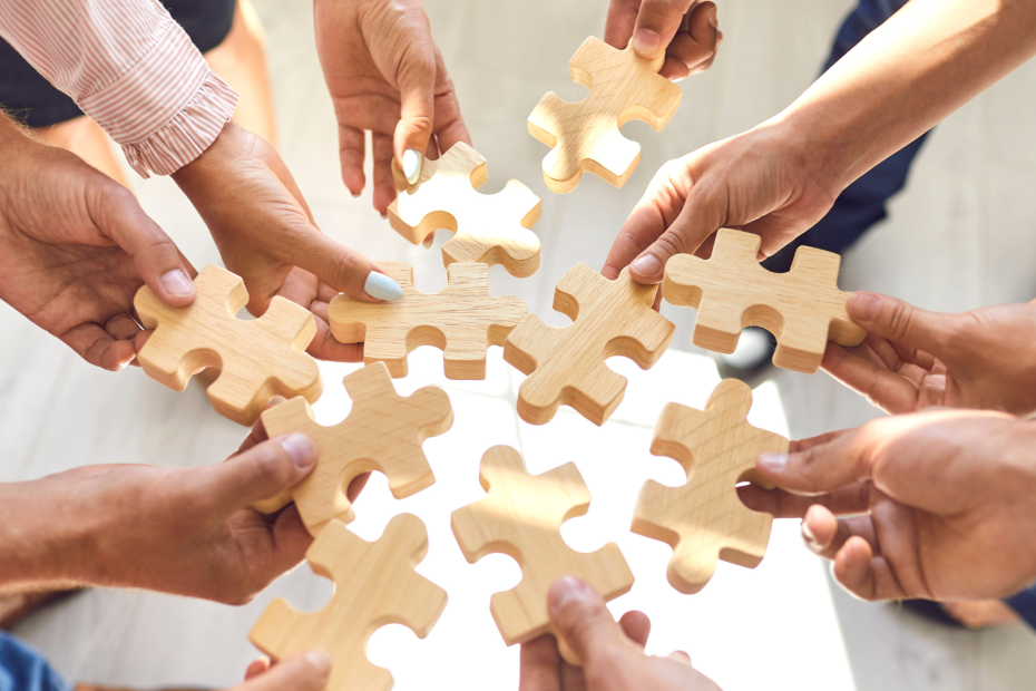 A group of people each holding a different puzzle piece.