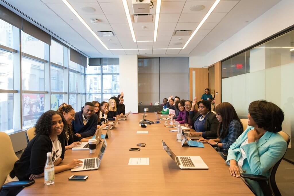 A large multi-ethnic team of men and women around a conference table, discussing wellness program engagement best practices