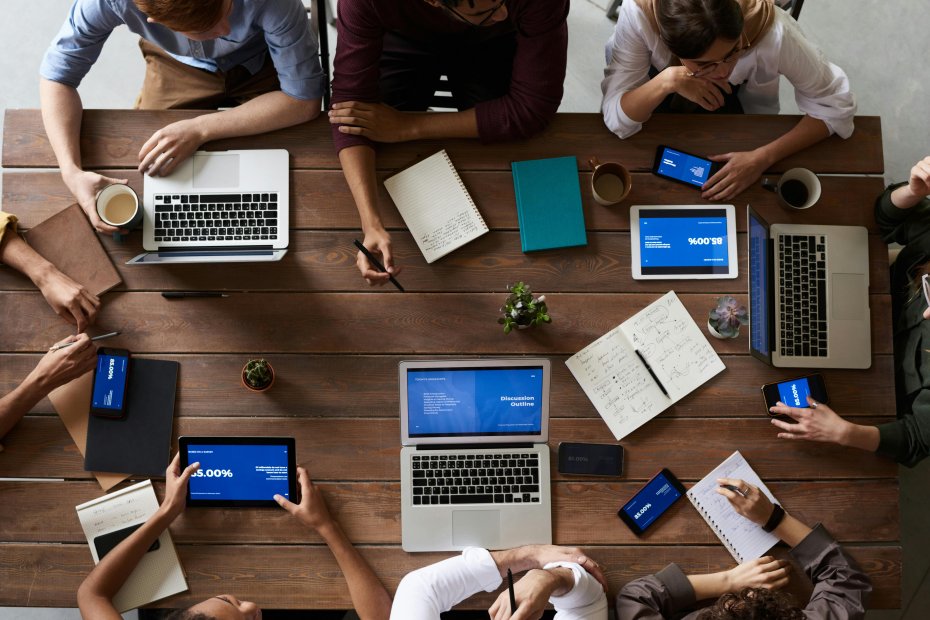Overhead view of multiple employees with computers and notbooks planning a program for wellness at work.