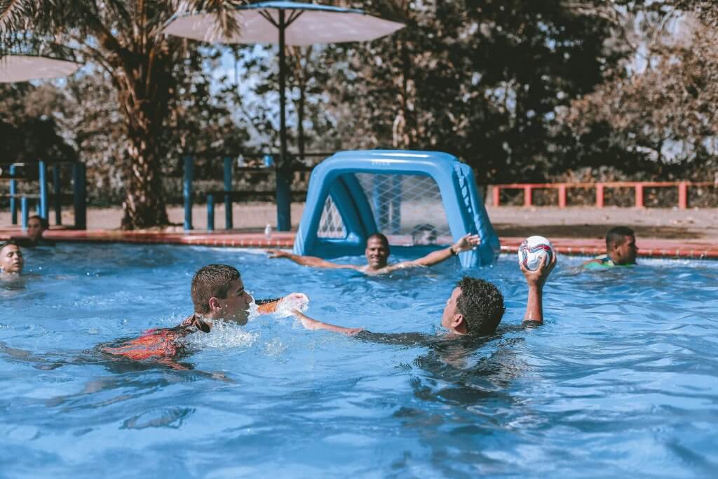 Grouo of men in a pool playing water polo after wellness was promoted at work.