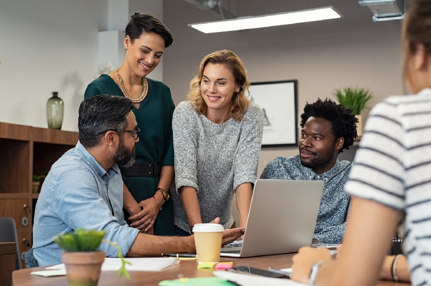 Multiethnic business people talking and smiling during meeting i people standing around desk